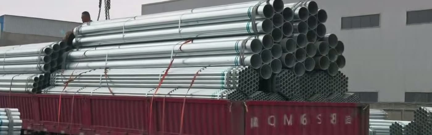 Galvanized pipe bundles stacked at the factory gate ready for loading